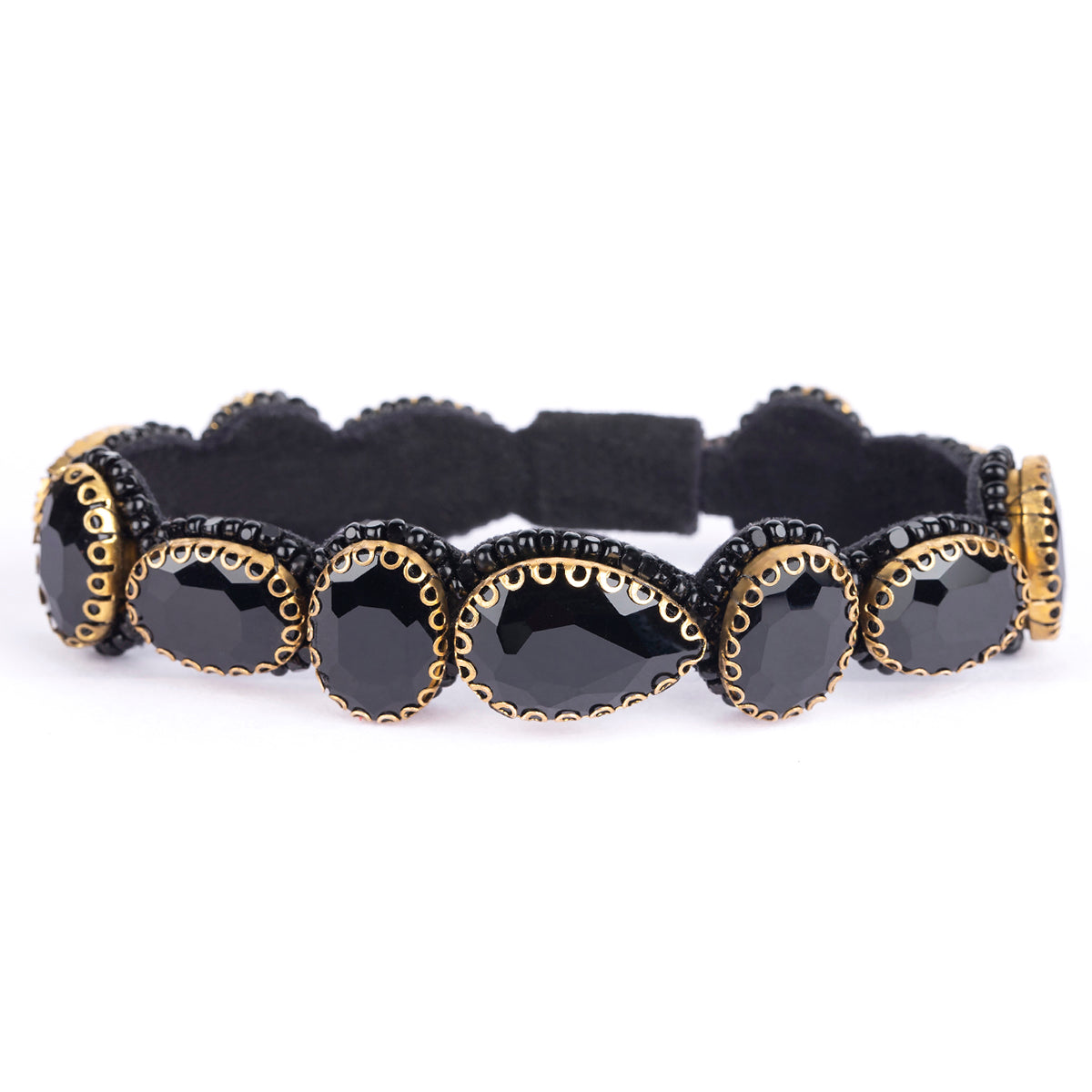 A black stretch bracelet featuring large oval black stones, each bordered by gold-tone metal and small black rhinestones, set against a plain white background.