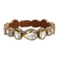A gold-tone cuff bracelet featuring five large oval-cut clear crystals and a brown leather inner band, shown against a plain white background.