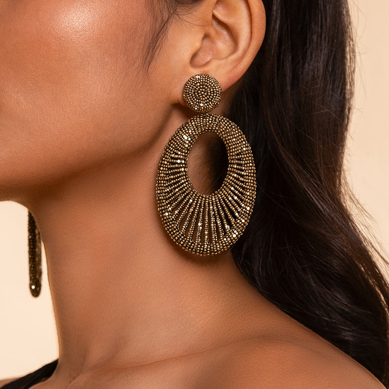 Detail of model wearing Deepa Gurnani Handmade Cypress Earrings in Antique Gold color