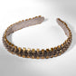 Decorative headband with brown and gold accents on a white background